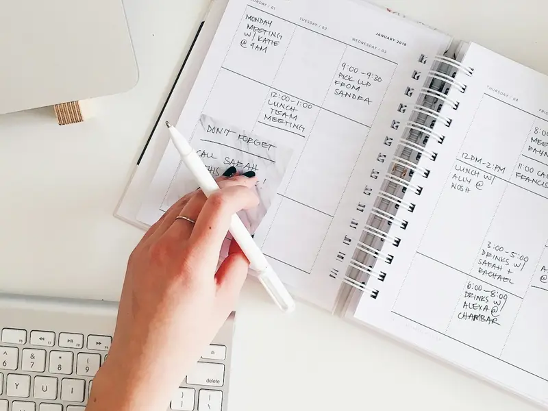 Una agenda abierta con la semana escrita a mano, junto a un teclado