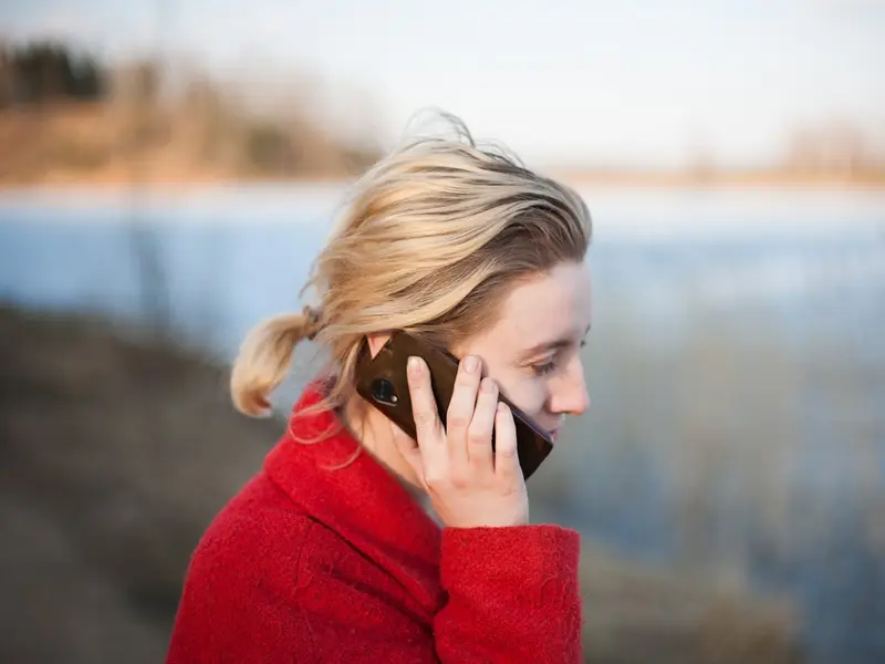Una mujer hablando por teléfono al aire libre, con el agua de fondo